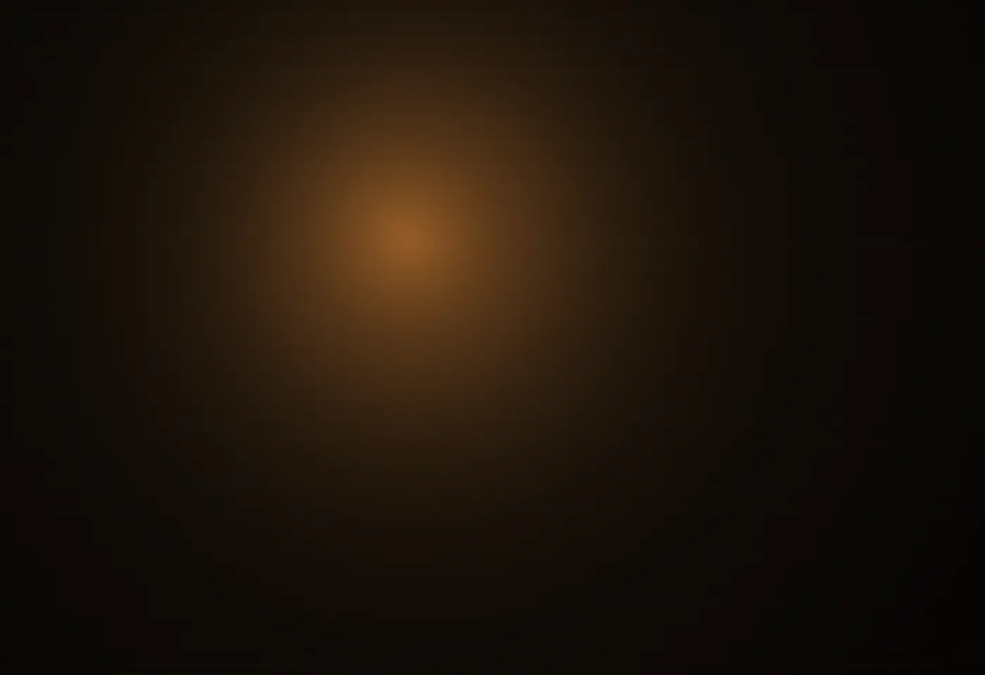 A warm pool of lamplight on a dark wooden table at evening